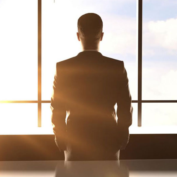 Rear view of a man in a suit in front of a window looking out | Management liability with NW Assekuranz