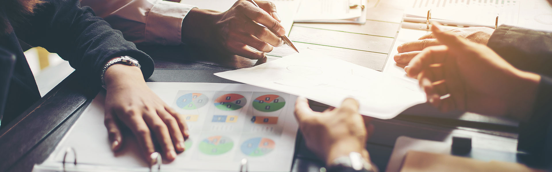 Vier Personen in einem Meeting: Nahaufnahme auf Hände und Tisch mit Papieren | Risikomanagement mit NW Assekuranz
