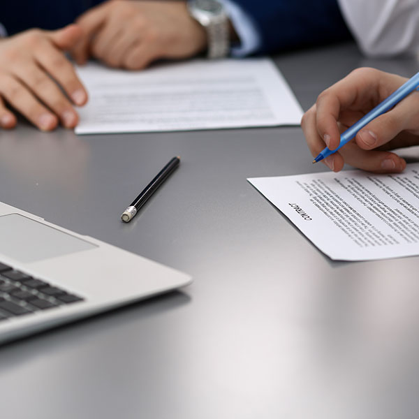 Two people at a table signing a contract | Contract Management with NW Assekuranz