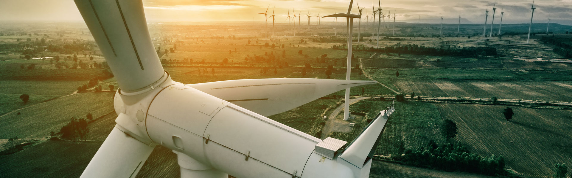Front view of the hub and nacelle of a wind turbine, in the background the remaining wind turbines of the wind farm | Risk coverage for full maintenance for onshore wind turbines with NW Assekuranz