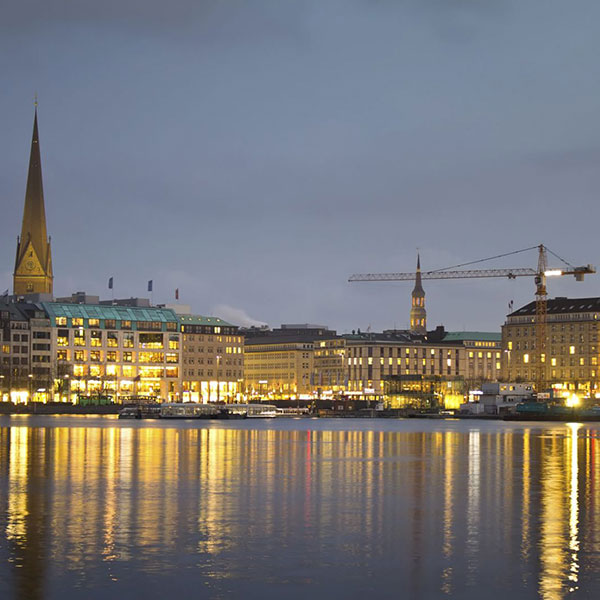 Illuminated buildings on the Binnenalster in Hamburg | NW Assekuranz is your partner for complex projects: Partial demolition & new construction of a property at the Rathausmarkt square in Hamburg