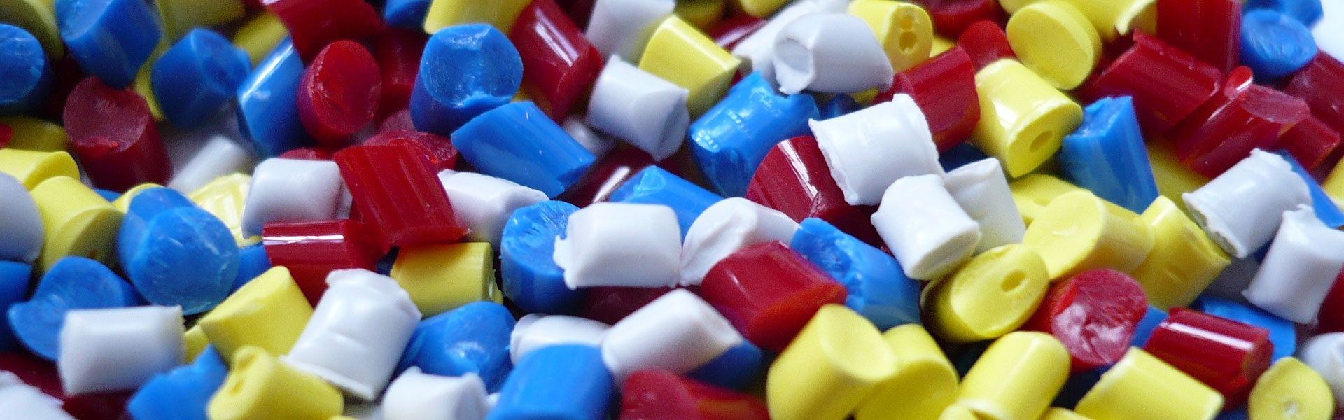 Plastic granules in blue, white, red and yellow | Risk management for the plastics industry with NW Assekuranz